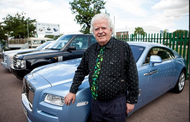 Rodger Dudding standing near his car collection. 