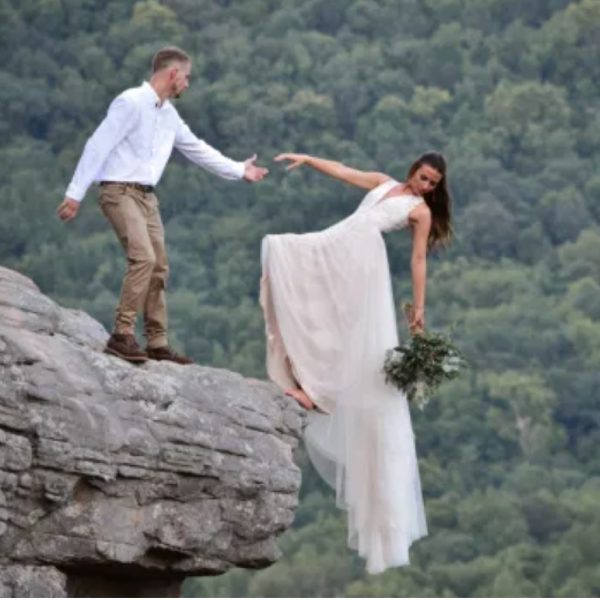 Bride and groom pose for wedding photo shoot hanging off the edge of a cliff (photos)